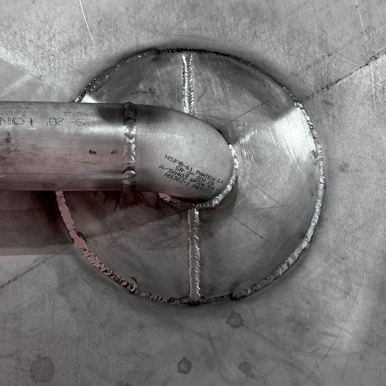 8-inch reinforcement pad welded around the 2-inch bottom drain, with the drain line elbow turning along the tank bottom
